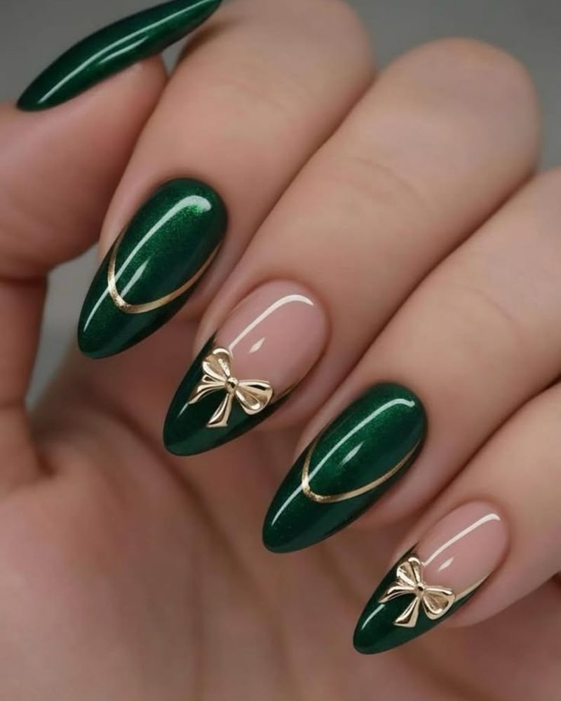 Almond nails in glossy emerald with gold half-moons and gold bows